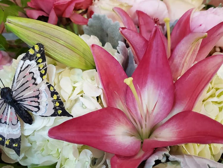 Pink lily blossoms in a cute, butterfly-themed arrangement